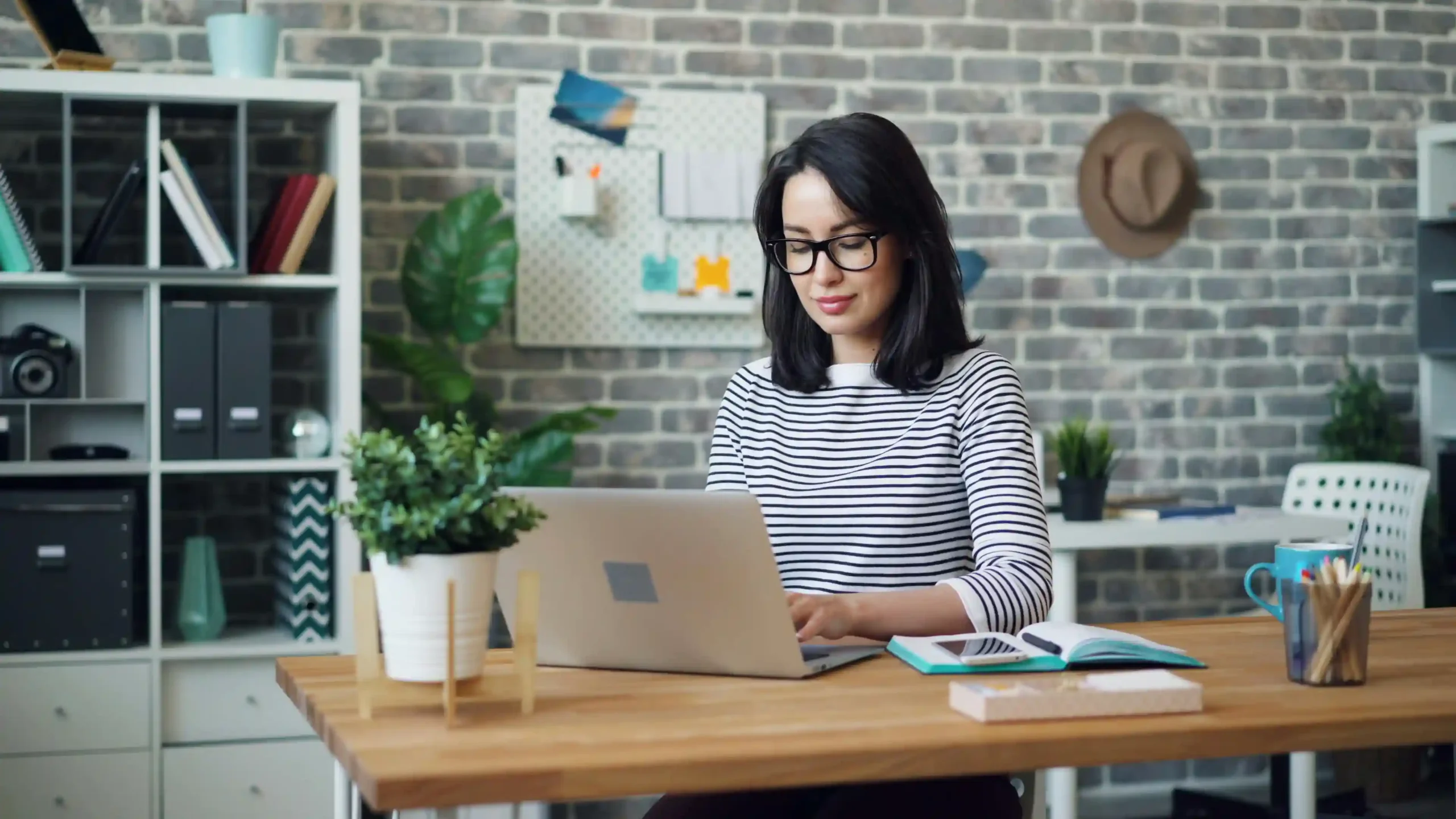A Young Small Business Owner Sitting at the Desk and Using the Laptop